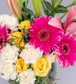 White carnation, pink lily, yellow rose, and pink gerbera in a vase