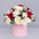 Red roses, white roses, and white carnation in pink box
