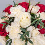 Red roses, white roses, and white carnation in pink box