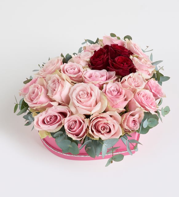 Rosa rosa, roja y eucalipto en caja de corazón