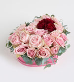 Rosa rosa, roja y eucalipto en caja de corazón