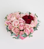 Rosa rosa, roja y eucalipto en caja de corazón