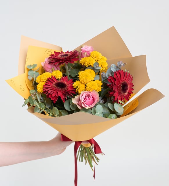 Gerberas rojas y rosas rosas en un ramo amarillo