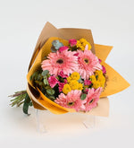 Rosas mini y gerberas rosas en un ramo amarillo