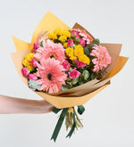 Rosas mini y gerberas rosas en un ramo amarillo