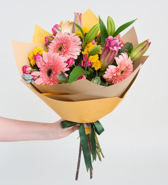 Gerbera rosa, mini rosas y lirios en ramo amarillo