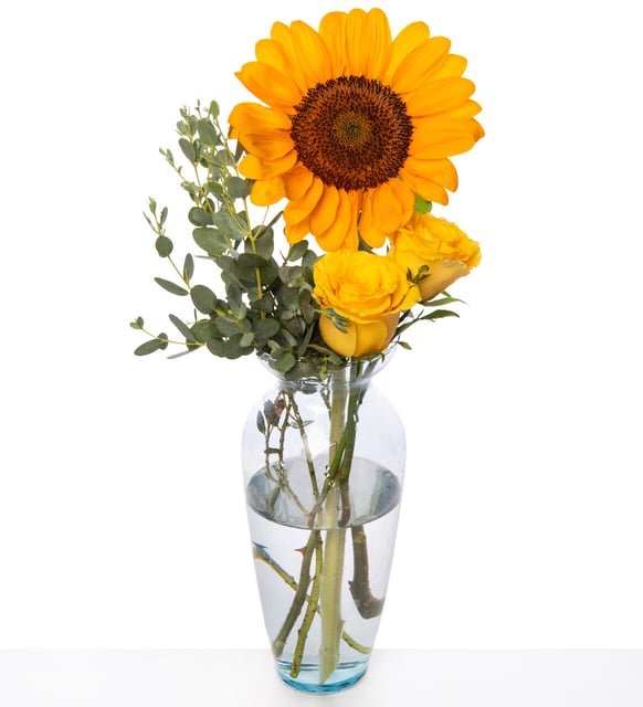 Girasoles y rosas amarillas en florero de vidrio