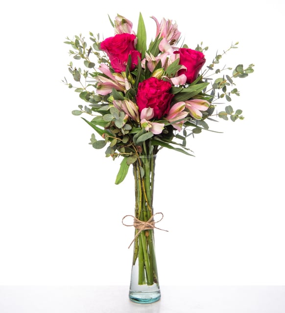 Rosas fucsias y flores astromelias rosas en florero de cristal