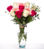 Rosas blancas, fucsias y gerberas rosas en florero de vidrio