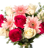 Rosas blancas, fucsias y gerberas rosas en florero de vidrio