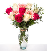 Rosas blancas, fucsias y gerberas rosas en florero de vidrio