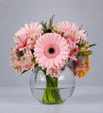 Yellow gerbera daisies and alstroemeria in a fishbowl vase