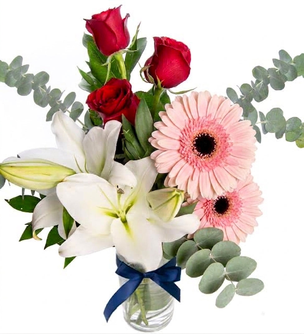 White lilies, red roses, and gerbera daisies in a vase