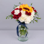 Roses and white carnation and sunflower in a glass vase