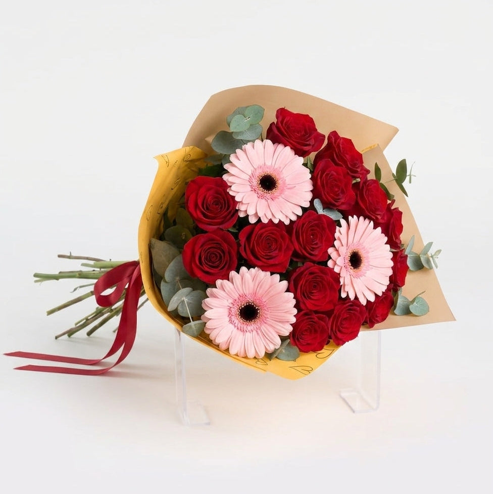 Red gerbera daisies and orange spray roses in a yellow bouquet